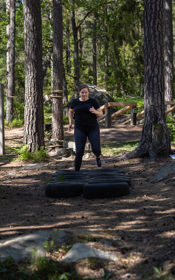 Emma William-Olsson springer bland däck i ett utegym.