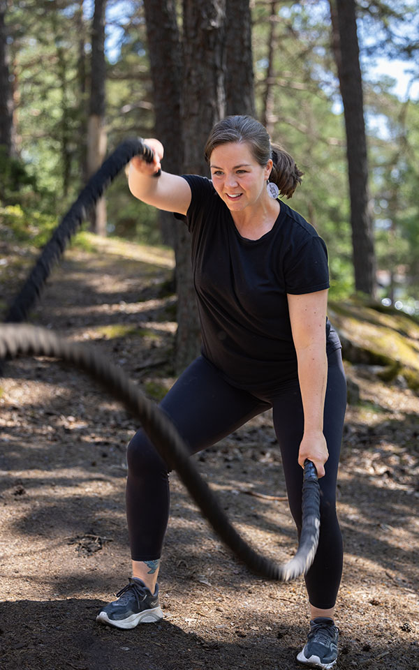 Emma William Olsson tränar med tunga rep i ett utegym. 